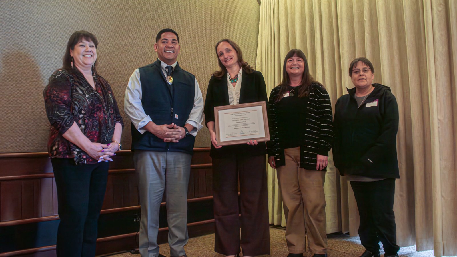 Tribal housing leaders and Federal Home Loan Bank partners with a framed recognition certificate at a NAIHC roundtable